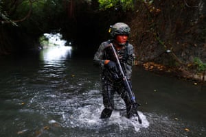 A trainee dressed in camouflage wades through sewage-contaminated water