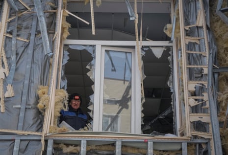 A local resident is seen in a broken window in a building damaged by a Russian military strike in Bakhmut, Ukraine.