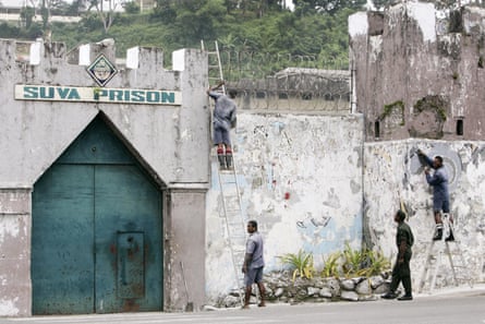 Inmates are watched by a guard, second,from right, as they work to strip a painted mural from the wall of the Suva Prison in the Fijian capitol.