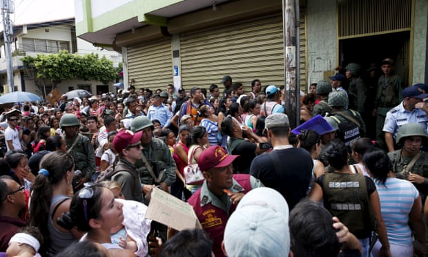 Venezuelan soldiers try to control the crowd queueing outside a supermarket while trying to buy staple items