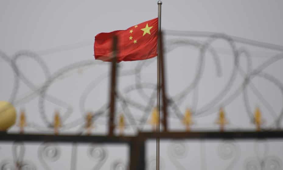 A picture taken in June 2019 shows the Chinese flag behind razor wire at a housing compound in Yangisar, in China’s Xinjiang region