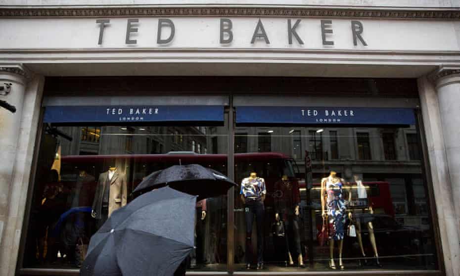 People shelter under umbrellas as they pass a Ted Baker store in London