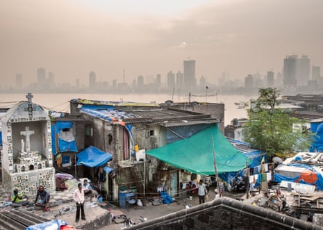 People stand in the streets of the fishing village of Worli, overlooking the residential buildings of Mahim, now a wealthy area of Mumbai. India, 2019