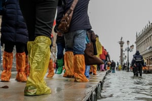 Tourists walk across emergency wooden boards in Saint Markâs Square which are used to create walkways over the high water in Venice, Italy.