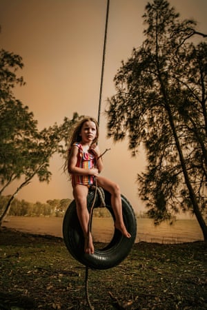 Photographer Shelley Reis's daughter, Lola, plays on a tyre swing with an ominous bushfire glow illuminating the background