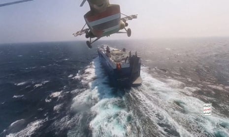 A Houthi military helicopter flies over the a cargo ship in the Red Sea.