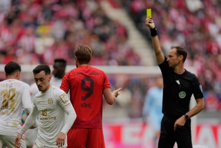 The referee Bastian Dankert shows a yellow card to Bayern Munich’s Harry Kane, who gestures in disbelief.