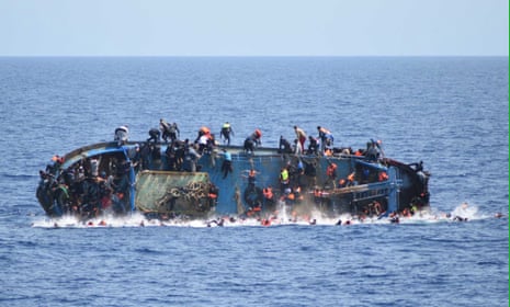Migrants in an overcrowded boat, which was about to capsize, are rescued by the Italian Navy