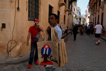 A man holds up handmade bags for sale to tourists in the street in Havana.