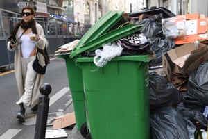 Paris, France. A pedestrian walks past full waste bins as rubbish collectors strike against pension changes