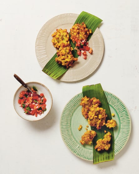 Overhead shot of crisp corn fritters on two plates, with a bowl of sambal on the side.
