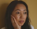 A slightly distressed middle-aged east Asian woman holds hand to her her face and looks off-camera