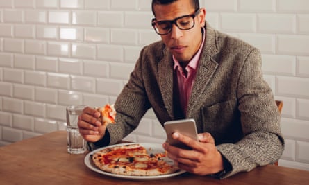 Man eating pizza alone looking at mobile