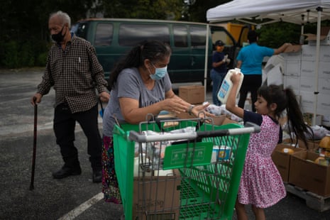 Amber, 5, helps her grandmother Minerva Delgado load groceries distributed by the Wesley Community Center to residents affected by the economic fallout caused by the coronavirus outbreak in Houston, Texas, US, on 24 July 2020.