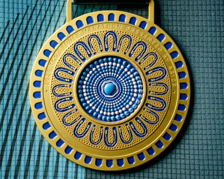 The reverse of the medal featuring an indigo and gold Indigenous design