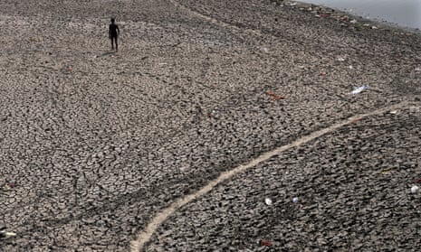 A man walks across a dried bed of the Yamuna River in New Delhi, India