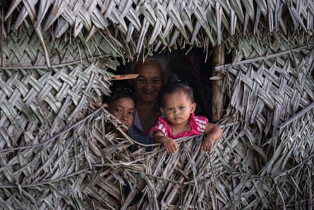 A Bajau family peek out from a gap in their stilt house on the shores of Bodgaya Island