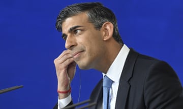 Rishi Sunak adjusting an earpiece at a press conference