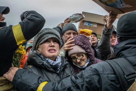 Kherson residents crowd around a volunteer aid truck to receive food