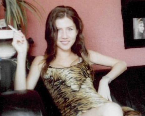 Anna Chapman, with long brown hair in a tiger-print dress, sits smiling, holding a cigarette