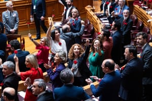 Portuguese deputies attend a solemn 50th anniversary commemorative session at the Portuguese parliament, some waving red carnations