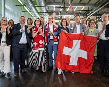 A group of politicians holding Swedish flags and clapping and cheering