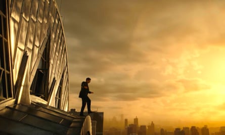 A figure looks over the edge of a building to a city sunset.
