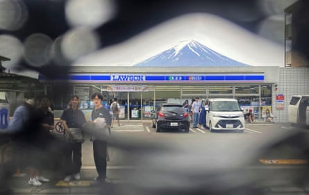 Mount Fuji can be seen through a hole in a black screen mounted across from a convenience store in the town of Fujikawaguchiko.