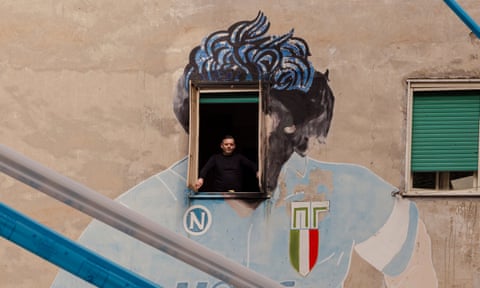 Ciro Maiello opens the window of his apartment in Naples, on which is painted the head of Diego Maradona.