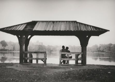 two people sitting on a bench in front of a body of water