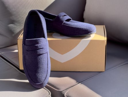 Navy blue Rothy’s slip on shoes next to box on couch