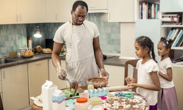 Father making cupcakes with children.