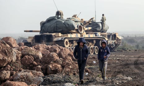 Two boys walk by Turkish army tanks in Afrin, Syria