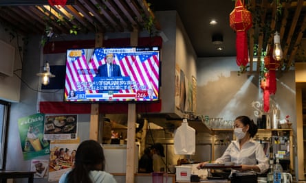 A TV screen broadcasts a news programme on the US election in a Tokyo restaurant with red lanterns