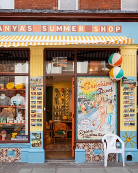 The exterior of a souvenir-style shop with the words ‘Anya’s summer shop’ above a yellow and white striped awning