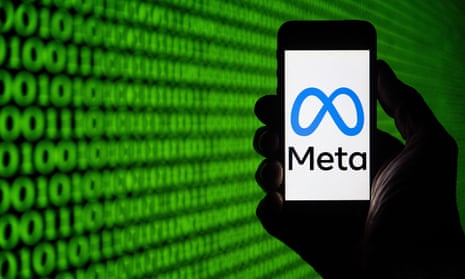 Stock photo of silhouetted hand holding up smartphone with blue infinity symbol logo of Meta, in front of screen of green 0's and 1's.