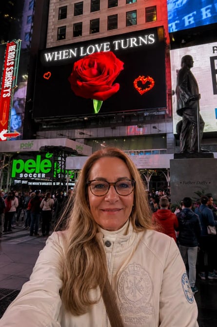 M L Stark smiles for a selfie in Times Square beneath a billboard advertising one of her novels, When Love Turns