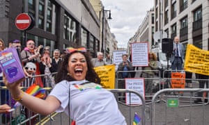 A lady takes a mocking selfie in front of protesters in Piccadilly