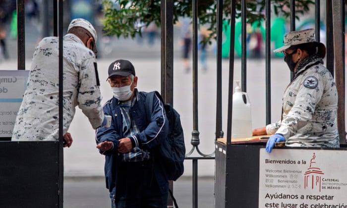 A member of National Guard wearing a face mask offers alcohol gel to a man as he enters to attend the first mass in the Metropolitan Cathedral following the resumption of activities, after measures and restrictions to fight the spread of coronavirus were eased in Mexico City.