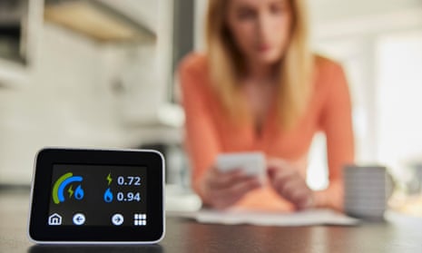 Close Up Of Smart Energy Meter In Kitchen Measuring Electricity And Gas Use With Woman Looking At Bills With Calculator
