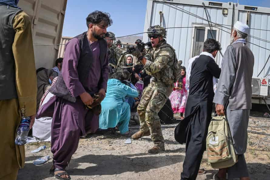 A US soldier (C) point his gun towards an Afghan passenger at the Kabul airport in Kabul on August 16, 2021