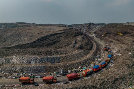 Garbage trucks queue beside one of the towering mounds of waste at the Bantar Gebang landfill