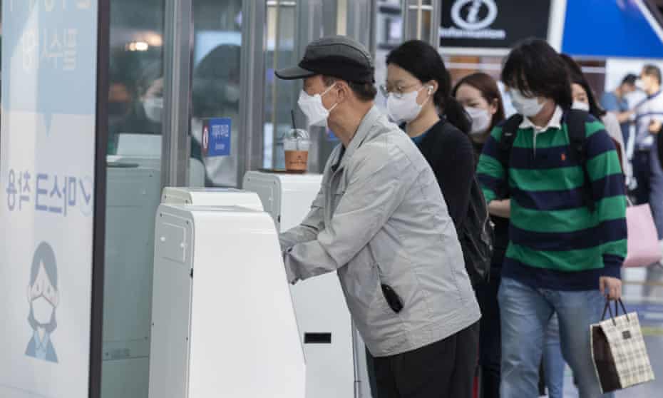 People wearing face masks sanitise their hands at Seoul Station in Seoul, South Korea.