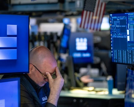 A trader at NYSE on Wall Street holds his head in his hands