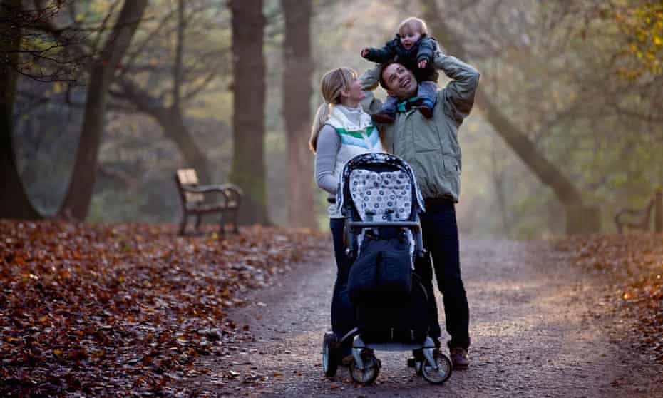 A family standing in the park, father carrying his son on his shoulders
