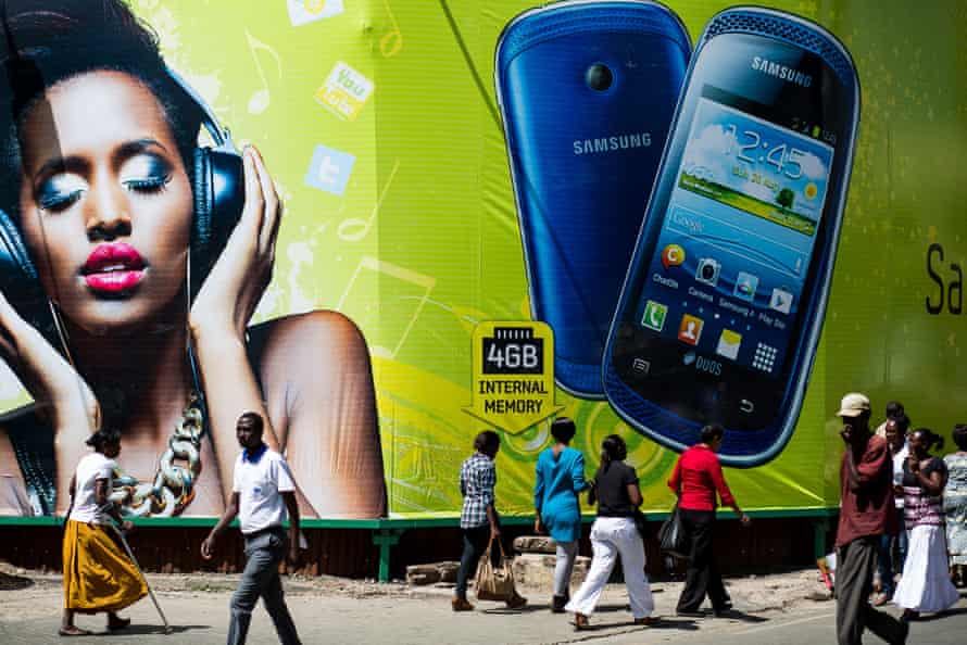 Pedestrians pass beneath a giant mobile phone advertisement in Nairobi, Kenya