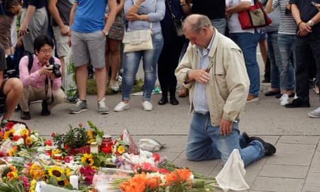 People mourn near the crime scene at OEZ shopping center the day after a shooting spree left nine victims dead in Munich.
