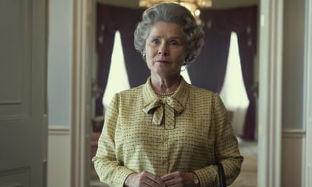 A woman with a grey hairset and a yellow dress in a grand room with curtain windows behind her