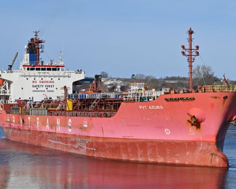 A large red cargo ship named PVT Azura sits in calm water.