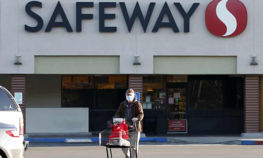 Wearing a mask for protection against the coronavirus, Henry Powell heads to his car after shopping at a Safeway store in Sacramento